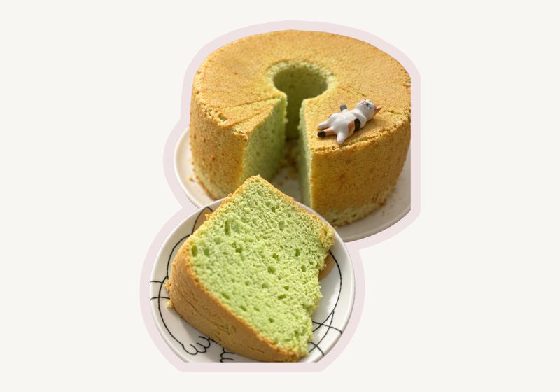Pandan chiffon cake with a slice cut and plated, topped with a small cat figurine