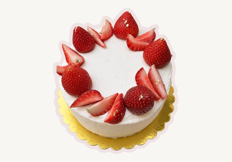 Strawberry shortcake ringed with fresh strawberries and gold leaf on a gold board